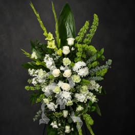 Tall white and green floral standing spray with ribbon on an easel