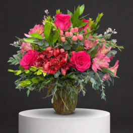 Pink roses and mixed blooms arranged in a glass vase
