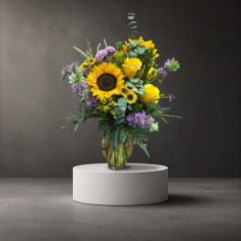 Sunflower and yellow rose arrangement in a glass vase