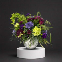 Purple and lime floral arrangement in a silver vase