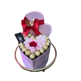 Heart-shaped box with pink roses and chocolates, topped with a red bow