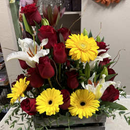 Red roses, white lilies, and yellow gerbera daisies in a wooden box