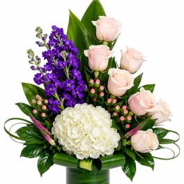 Pink roses and purple flowers in a green glass vase with white hydrangea