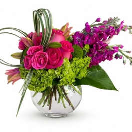 Pink roses and purple flowers in a clear glass vase