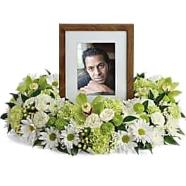 Low white and green floral ring encircling a wooden photo frame with a portrait