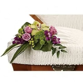 Purple and green floral spray on a white casket