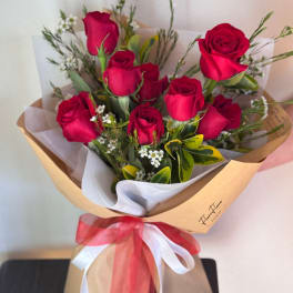 Bouquet of red roses wrapped in brown paper with a red and white ribbon