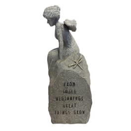Stone figurine of a seated child on a rock with an engraved quote