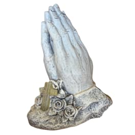 Praying hands statue with roses and a cross