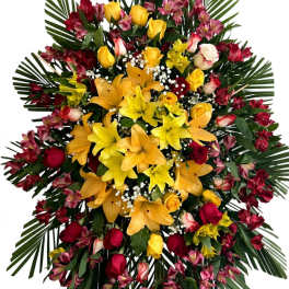 Large standing floral spray with yellow lilies, red roses, and pink blooms