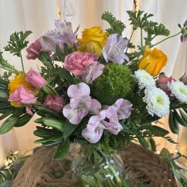 Mixed bouquet of pink, yellow, and white flowers in a glass vase