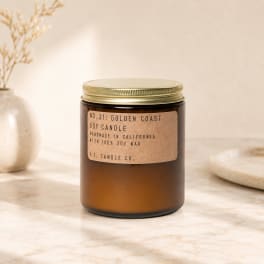 Amber soy candle in a glass jar with a gold lid and label
