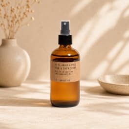 Amber room spray bottle with a black pump on a neutral tabletop
