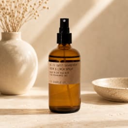 Amber room spray bottle with black pump on a neutral tabletop