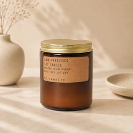 Amber jar candle with a gold lid on a neutral tabletop