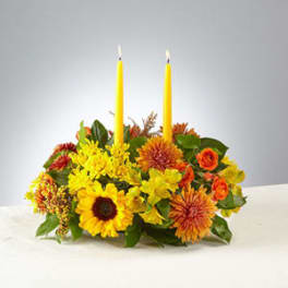 Low floral centerpiece with two yellow taper candles