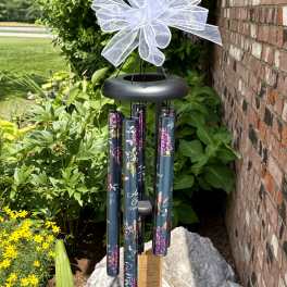 Black wind chime with a white bow hanging outdoors