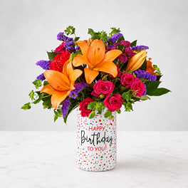 Bouquet of orange lilies and pink roses in a birthday vase