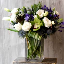 White and purple flowers arranged in a clear glass vase