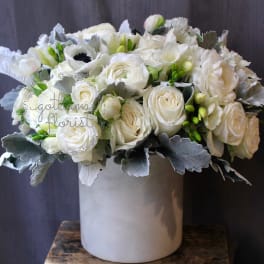 White rose bouquet in a tall gray vase with silver foliage