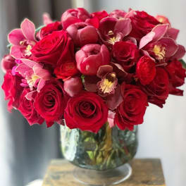 Red roses and pink orchids arranged in a glass vase