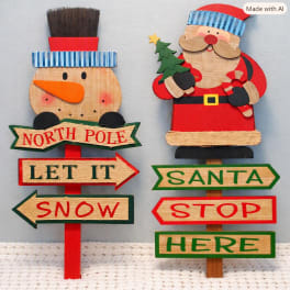 Wooden Christmas signs with a snowman and Santa holding a tree.