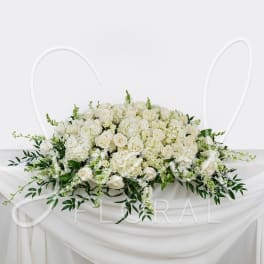 White rose and hydrangea arrangement on a draped table