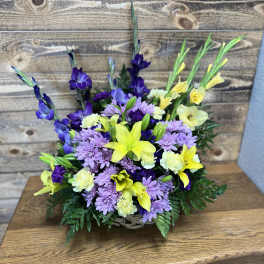 Basket arrangement of purple daisies and yellow lilies