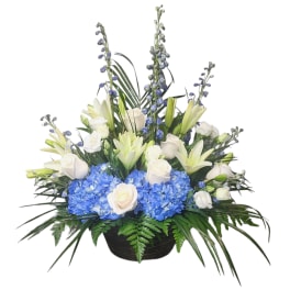 White roses and lilies with blue hydrangeas in a black basket