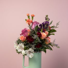 Mixed bouquet in a mint tumbler-style vase on a pedestal