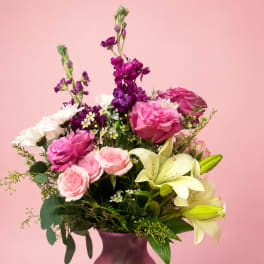 Pink and purple bouquet with lilies and roses in a purple vase