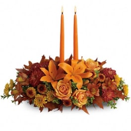 Autumn floral centerpiece with two orange taper candles