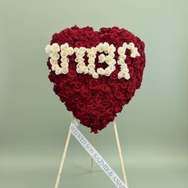 Heart-shaped rose arrangement on a stand with white lettering