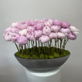 Pink peonies arranged in a shallow gray bowl
