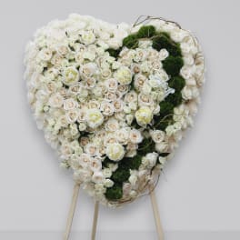 Heart-shaped floral arrangement of white and blush roses with green moss accents