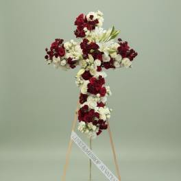Cross-shaped floral tribute of red and white roses on a stand