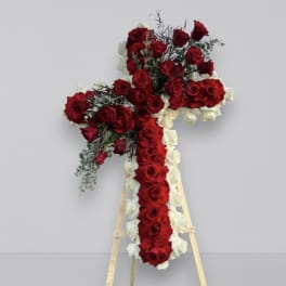 Cross-shaped floral tribute of red and white roses on a wooden easel