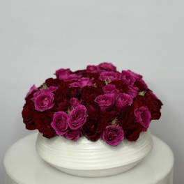 Round arrangement of pink and deep red roses in a white bowl vase