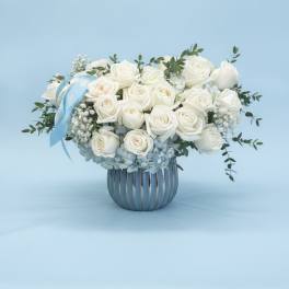 White rose bouquet in a silver vase with a blue ribbon