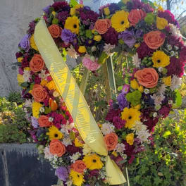 Heart-shaped floral wreath on an easel with a yellow ribbon