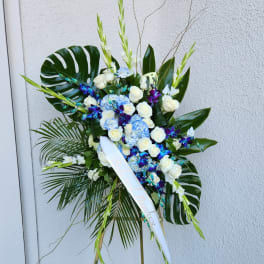 Tall standing floral spray with white roses, blue hydrangeas, and purple orchids