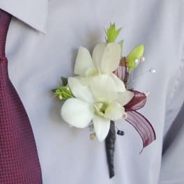 White orchid boutonniere with burgundy ribbon on a shirt lapel