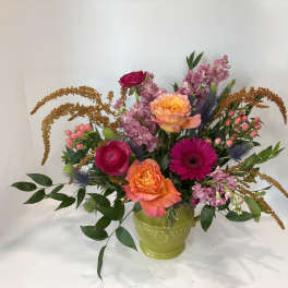 Mixed bouquet of roses, gerbera daisies, and pink blooms in a green vase