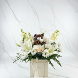 White floral arrangement with a small teddy bear in a Dior gift box