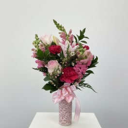 Pink and white mixed bouquet in a patterned vase with a pink ribbon