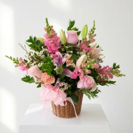 Pink floral basket arrangement with roses, lilies, and snapdragons