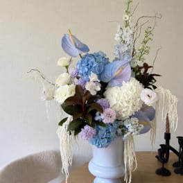 Large pastel floral arrangement in a white vase on a table