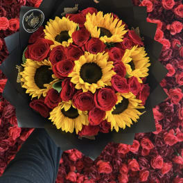 Bouquet of red roses and yellow sunflowers wrapped in black paper