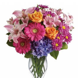 Bright mixed bouquet of pink, orange, and purple flowers in a clear glass vase