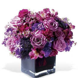 Compact arrangement of purple and pink flowers in a square glass vase